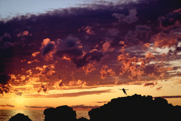 man diving with dramatic sky behind him